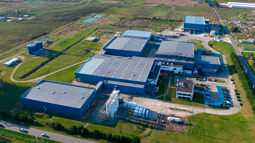 Vista aérea de una planta industrial terminada, rodeada de caminos, depósitos y áreas verdes